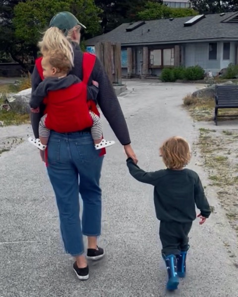 Chanlyn walking a path with her two sons, one in a carrier and one holding her hand